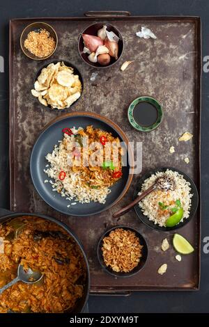 Una vista ad alto angolo del jackfruit indonesiano vegano fatto in casa rendang servito con riso su un piatto nero e accompagnamenti Foto Stock