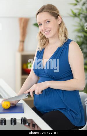 incinta in cucina prepara il tè al limone Foto Stock