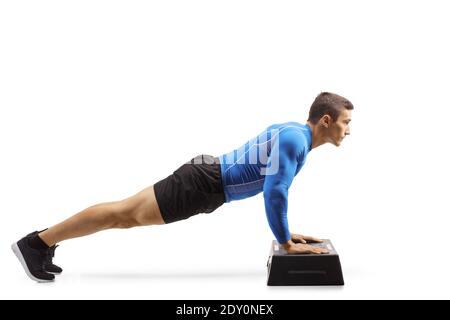 L'uomo muscolare che esercita i push-up su una piattaforma aerobica passo isolato su sfondo bianco Foto Stock