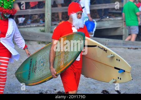 Indialantic, Contea di Brevard, Florida, Stati Uniti. 24 dicembre 2020. La vigilia di Natale Surf Santa 2020 è stato un evento ridotto quest'anno a causa del Covid-19. Un piccolo gruppo vestito di abbigliamento natalizio si avventurò nel frangente surf dell'Oceano Atlantico mentre qualche centinaio di spettatori guardavano dalla spiaggia. Credit: Julian Leek/Alamy Live News Foto Stock