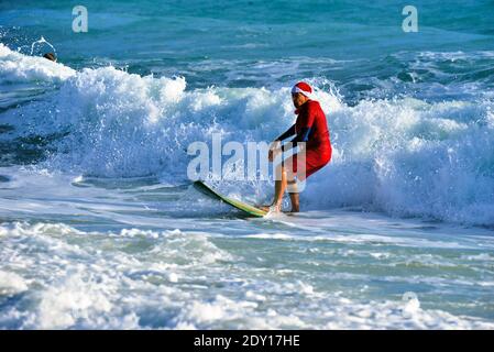 Indialantic, Contea di Brevard, Florida, Stati Uniti. 24 dicembre 2020. La vigilia di Natale Surf Santa 2020 è stato un evento ridotto quest'anno a causa del Covid-19. Un piccolo gruppo vestito di abbigliamento natalizio si avventurò nel frangente surf dell'Oceano Atlantico mentre qualche centinaio di spettatori guardavano dalla spiaggia. Credit: Julian Leek/Alamy Live News Foto Stock