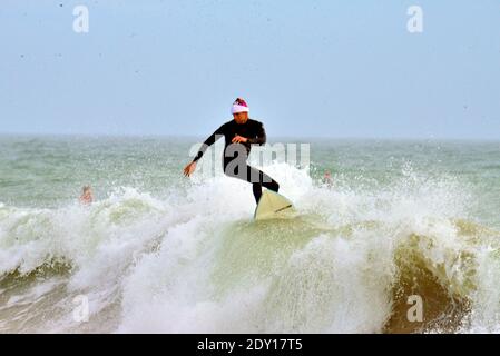 Indialantic, Contea di Brevard, Florida, Stati Uniti. 24 dicembre 2020. La vigilia di Natale Surf Santa 2020 è stato un evento ridotto quest'anno a causa del Covid-19. Un piccolo gruppo vestito di abbigliamento natalizio si avventurò nel frangente surf dell'Oceano Atlantico mentre qualche centinaio di spettatori guardavano dalla spiaggia. Credit: Julian Leek/Alamy Live News Foto Stock