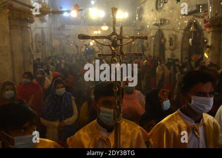 I cristiani pakistani adorano la messa di Natale di metà notte in vista delle celebrazioni natalizie nella Chiesa di Sant'Antonio a Lahore. Foto Stock