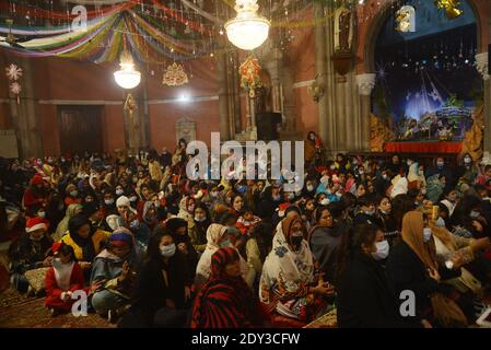 I cristiani pakistani adorano la messa di Natale di metà notte in vista delle celebrazioni natalizie nella Chiesa di Sant'Antonio a Lahore. Foto Stock