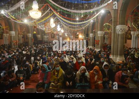 I cristiani pakistani adorano la messa di Natale di metà notte in vista delle celebrazioni natalizie nella Chiesa di Sant'Antonio a Lahore. Foto Stock