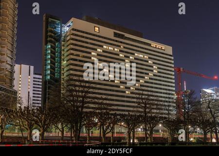 Grattacieli dello skyline di notte in una città di Francoforte. Le finestre individuali sono illuminate e formano un cuore. Alberi singoli e luci di strada nel Foto Stock