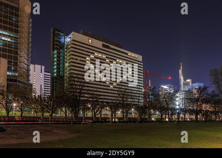 Grattacieli di notte nella città di Francoforte. Le finestre individuali sono illuminate e formano un cuore. Corona Action resta a casa. Alberi singoli e stree Foto Stock