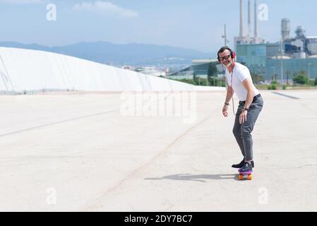 L'uomo con le cuffie ama guidare uno skateboard attraverso la città Foto Stock