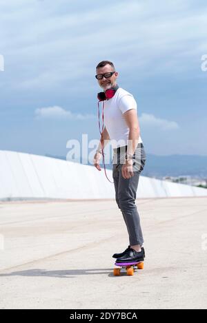 L'uomo con le cuffie ama guidare uno skateboard attraverso la città Foto Stock