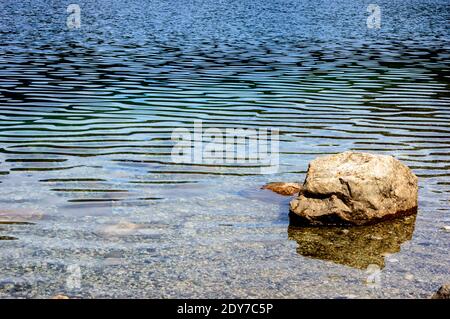 Roccia nel lago cristallino. Bariloche giorno d'estate. Foto Stock