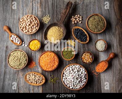 Vegan proteina source. Vario assortimento di legumi, lenticchie, ceci e fagioli assortimenti in diverse ciotole su tavola di legno. Vista dall'alto. Foto Stock