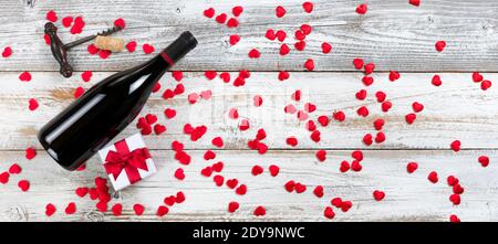 Bottiglia completa di vino rosso più scatola regalo con un po' di rosso cuori graziosi su legno naturale rustico bianco in fieno Composizione per il concetto di giorno di San Valentino Foto Stock