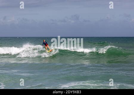 Una surfista femminile corre un'onda lungo l'isola di Hutchinson a Stuart, Florida, Stati Uniti. Foto Stock