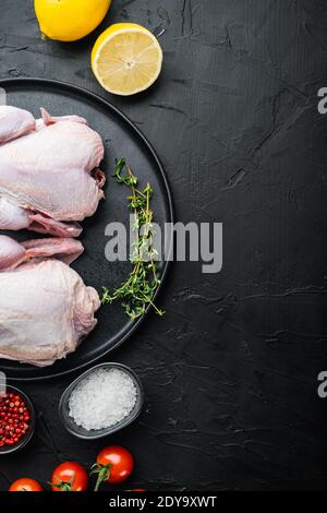 Pollo fresco crudo intero con spezie alle erbe, su sfondo nero, vista dall'alto con spazio per la copia del testo Foto Stock