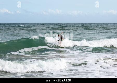 Un surfista corre un'onda lungo l'isola di Hutchinson a Stuart, Florida, Stati Uniti. Foto Stock