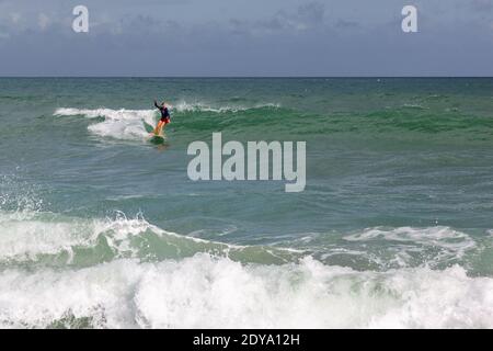 Una surfista femminile corre un'onda lungo l'isola di Hutchinson a Stuart, Florida, Stati Uniti. Foto Stock