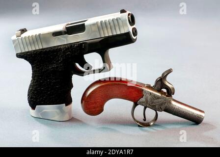 Vecchia scuola e nuove pistole scuola, una con 40 calibro semi auto e cappello e palla antico. Foto Stock