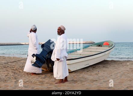 Uomini Omani in piedi presso la loro barca da pesca a sur, Oman. Foto Stock