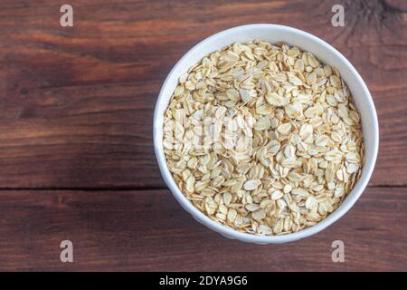 Fiocchi d'avena grandi tradizionali in una ciotola su uno sfondo di legno con una copia dello space.The vista dall'alto. Foto Stock