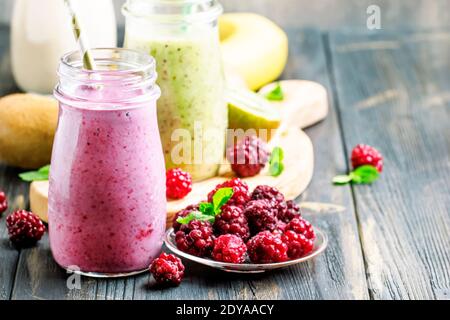 Frullati multicolore di frutti di bosco e frutta, assortiti in bottiglie di vetro, fuoco selettivo Foto Stock