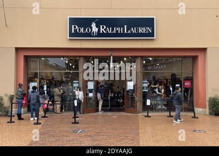 La gente si trova in fila fuori dal negozio Polo Ralph Lauren il giorno prima di Natale presso la Cittadella Outles in mezzo al coronavirus globale COVID-19 pandemia, Foto Stock