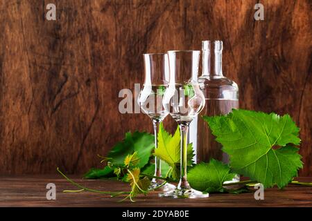 Vodka d'uva, pisco - bevanda alcolica forte peruviana tradizionale in bicchieri eleganti su tavolo di legno d'annata, spazio copia Foto Stock