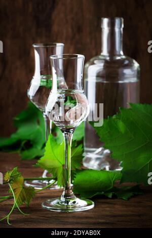 Vodka d'uva, pisco - bevanda alcolica forte peruviana tradizionale in bicchieri eleganti su tavolo di legno d'annata, spazio copia Foto Stock