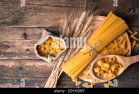 Pasta e spighe di grano su un tagliere su fondo di legno. Foto Stock