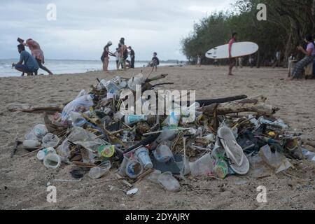 Badung, Bali, Indonesia. 20 dicembre 2020. I turisti sono visti lungo la spiaggia tra le trashes.tons di Trash riferito scaricato nei fiumi dai cittadini, e trasportato sulla spiaggia durante la stagione delle piogge. Credit: Dicky Bisinglasi/SOPA Images/ZUMA Wire/Alamy Live News Foto Stock