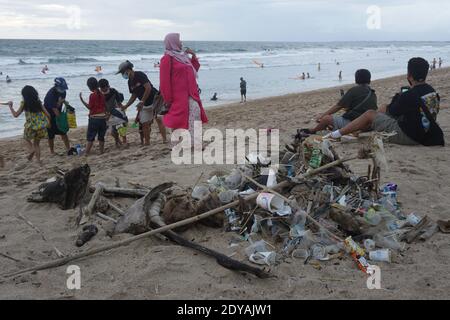 Badung, Bali, Indonesia. 20 dicembre 2020. I turisti sono visti lungo la spiaggia tra le trashes.tons di Trash riferito scaricato nei fiumi dai cittadini, e trasportato sulla spiaggia durante la stagione delle piogge. Credit: Dicky Bisinglasi/SOPA Images/ZUMA Wire/Alamy Live News Foto Stock