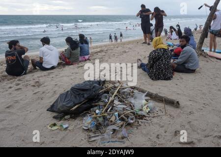 Badung, Bali, Indonesia. 20 dicembre 2020. I turisti si siedono vicino ai trashes lungo la spiaggia di Kuta di Bali.Tons di Trash, secondo quanto riferito, scaricato nei fiumi dai cittadini, e trasportato sulla spiaggia durante la stagione delle piogge. Credit: Dicky Bisinglasi/SOPA Images/ZUMA Wire/Alamy Live News Foto Stock