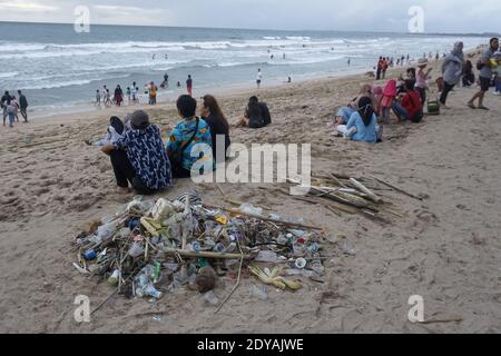 Badung, Bali, Indonesia. 20 dicembre 2020. I turisti si siedono vicino ai trashes lungo la spiaggia di Kuta di Bali.Tons di Trash, secondo quanto riferito, scaricato nei fiumi dai cittadini, e trasportato sulla spiaggia durante la stagione delle piogge. Credit: Dicky Bisinglasi/SOPA Images/ZUMA Wire/Alamy Live News Foto Stock