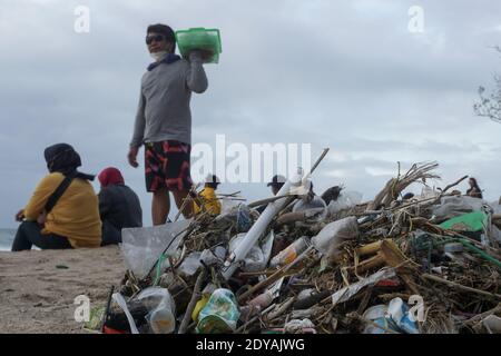 Badung, Bali, Indonesia. 20 dicembre 2020. I turisti si siedono vicino ai trashes lungo la spiaggia di Kuta di Bali.Tons di Trash, secondo quanto riferito, scaricato nei fiumi dai cittadini, e trasportato sulla spiaggia durante la stagione delle piogge. Credit: Dicky Bisinglasi/SOPA Images/ZUMA Wire/Alamy Live News Foto Stock