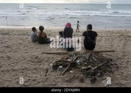 Badung, Bali, Indonesia. 20 dicembre 2020. I turisti si siedono vicino ai trashes lungo la spiaggia di Kuta di Bali.Tons di Trash, secondo quanto riferito, scaricato nei fiumi dai cittadini, e trasportato sulla spiaggia durante la stagione delle piogge. Credit: Dicky Bisinglasi/SOPA Images/ZUMA Wire/Alamy Live News Foto Stock