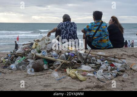 Badung, Bali, Indonesia. 20 dicembre 2020. I turisti si siedono vicino ai trashes lungo la spiaggia di Kuta di Bali.Tons di Trash, secondo quanto riferito, scaricato nei fiumi dai cittadini, e trasportato sulla spiaggia durante la stagione delle piogge. Credit: Dicky Bisinglasi/SOPA Images/ZUMA Wire/Alamy Live News Foto Stock