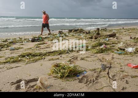 Badung, Bali, Indonesia. 20 dicembre 2020. Un uomo cammina lungo la spiaggia tra i trashes.tons di Trash riferito scaricato nei fiumi dai cittadini, e portato sulla spiaggia durante la stagione delle piogge. Credit: Dicky Bisinglasi/SOPA Images/ZUMA Wire/Alamy Live News Foto Stock