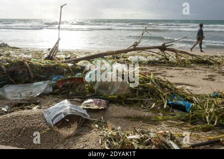 Badung, Bali, Indonesia. 20 dicembre 2020. Un uomo cammina lungo la spiaggia tra i trashes.tons di Trash riferito scaricato nei fiumi dai cittadini, e portato sulla spiaggia durante la stagione delle piogge. Credit: Dicky Bisinglasi/SOPA Images/ZUMA Wire/Alamy Live News Foto Stock