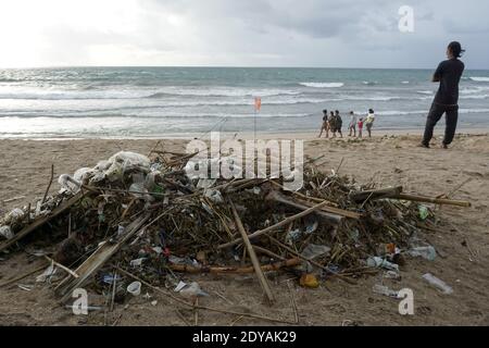 Badung, Bali, Indonesia. 20 dicembre 2020. I turisti sono visti lungo la spiaggia tra le trashes.tons di Trash riferito scaricato nei fiumi dai cittadini, e trasportato sulla spiaggia durante la stagione delle piogge. Credit: Dicky Bisinglasi/SOPA Images/ZUMA Wire/Alamy Live News Foto Stock