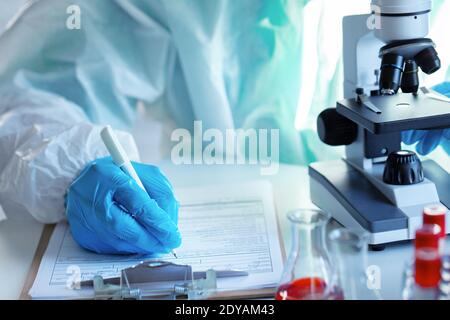 Primo piano delle mani del medico che prende appunti sul tavolo Foto Stock