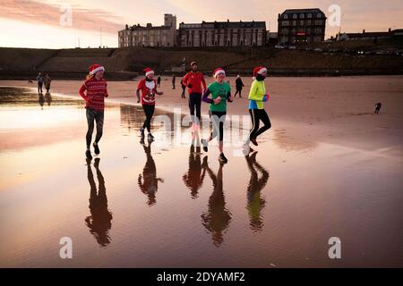 I joggers prendono una corsa di Natale di mattina presto lungo la spiaggia di Tynemouth sulla costa nordorientale dell'Inghilterra. Foto Stock