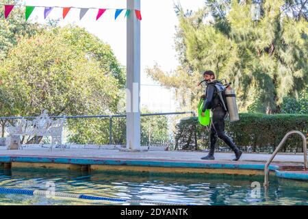 tuffatore che cammina in piscina dopo la sua lezione di immersione Foto Stock