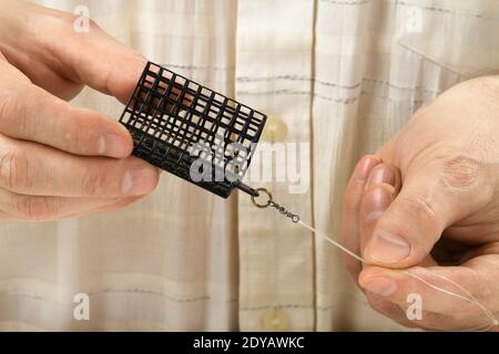 l'alimentatore a gabbia è nelle mani del pescatore, primo piano Foto Stock