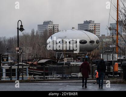 Berlino, Germania. 25 Dic 2020. Un edificio simile a un UFO sorge su una nave non lontano dall'isola di Berlino. Si tratta di una casa chiamata 'futuro' dall'architetto finlandese Matti Suuronen. La casa rotonda, in gran parte in plastica, si trovava per molti anni nel primo parco culturale della RDT a Treptow. Credit: Paul Zinken/dpa/Alamy Live News Foto Stock