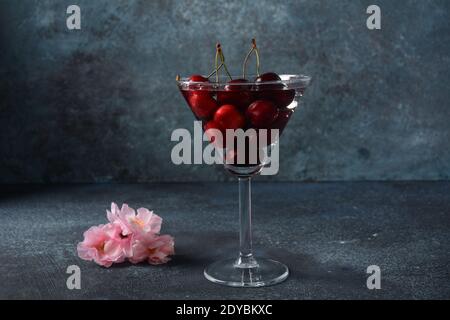 Ciliegie rosse dolci in un bicchiere. Primo piano di ciliegio in un bicchiere con gocce d'acqua. Dolce estivo Foto Stock