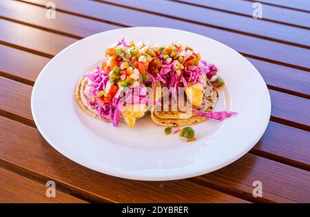 Red Snapper Fish Tacos su piatto bianco e tavolo in legno Foto Stock