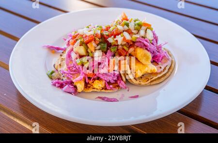 Red Snapper Fish Tacos su piatto bianco e tavolo in legno Foto Stock