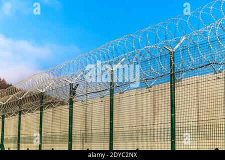 Filo spinato contro un cielo blu. Concetto di prigione. Ordine di inserimento. Base militare. Dettaglio di New Fence con filo a spirale Foto Stock