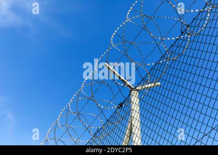 Filo spinato contro un cielo blu. Concetto di prigione. Ordine di inserimento. Base militare. Dettaglio di New Fence con filo a spirale Foto Stock