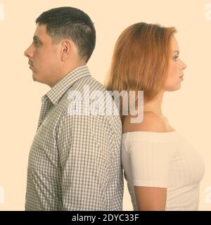 Studio di giovane coppia con le spalle l'una contro l'altra Foto Stock