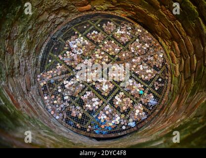 Vista direttamente dall'alto di un pozzo augurante con molte monete sul fondo all'interno del Palazzo dei Priori (XIII secolo) di Volterra, Pisa, Toscana, Italia Foto Stock